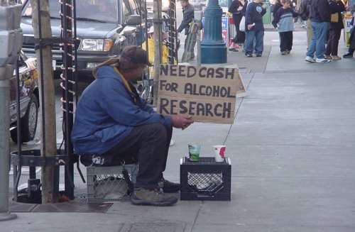 preciso de grana para realizar pesquisas com alcool mendigo segurando placa
